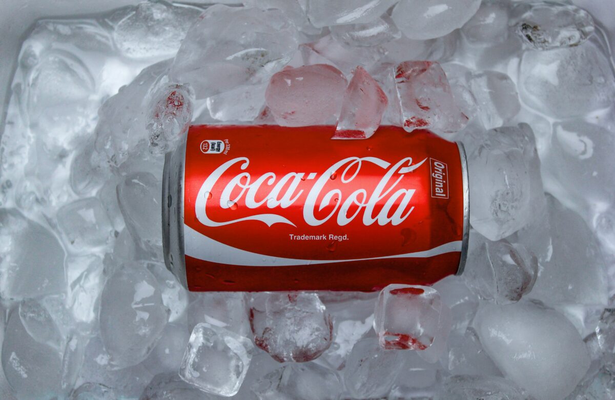 A Coca-Cola can lying on ice, showcasing the iconic red label and branding.