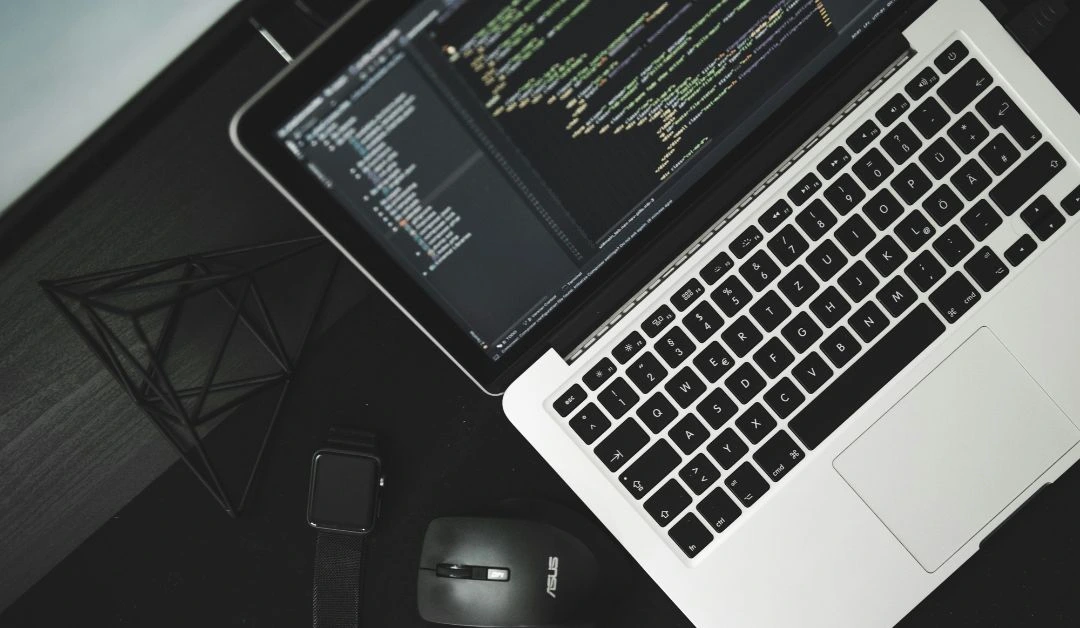 MacBook Pro on a wooden desk in a dimly lit workspace, symbolizing Cincinnati’s thriving tech and startup culture.