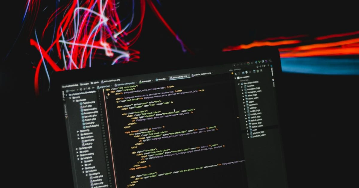 Laptop displaying HTML code with red and blue light trails in a Nashville workspace.