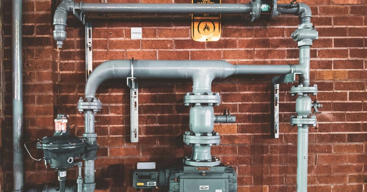 Industrial plumbing system with gray pipes mounted on a red brick wall in Nashville.