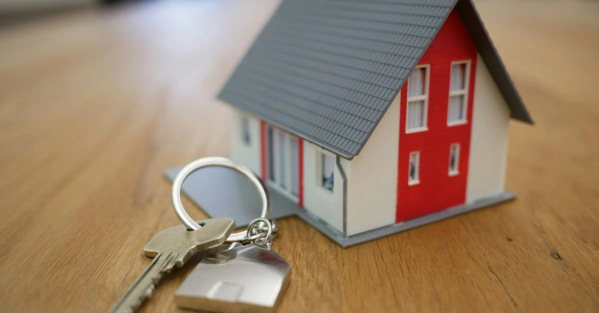 A small model house with a set of keys on a wooden table, symbolizing homeownership in Nashville.